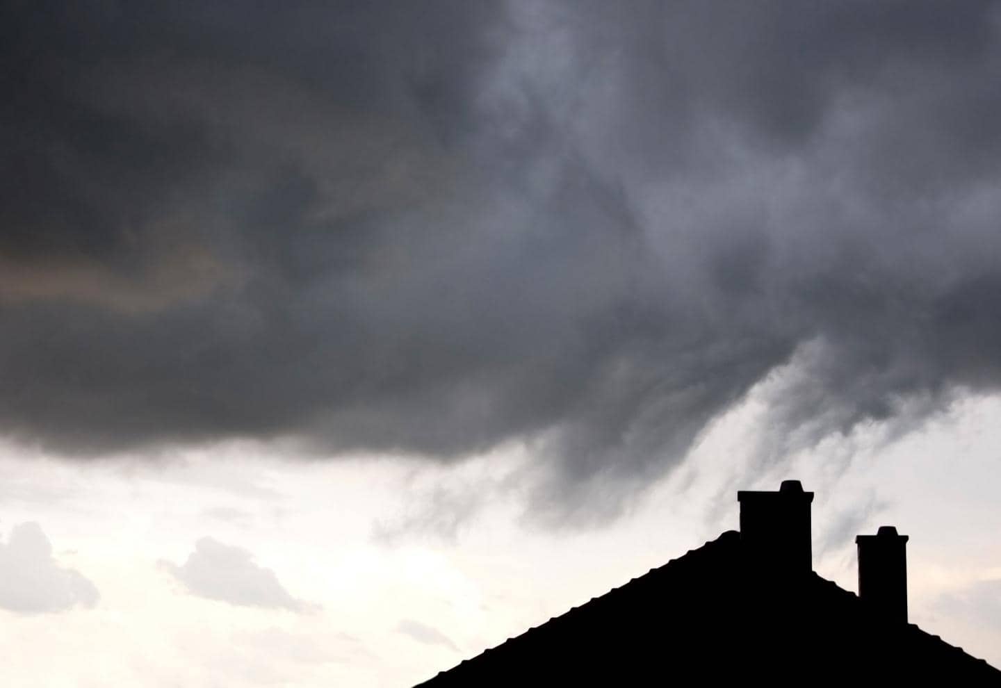 Mørk og stormfuld himmel over et hustag