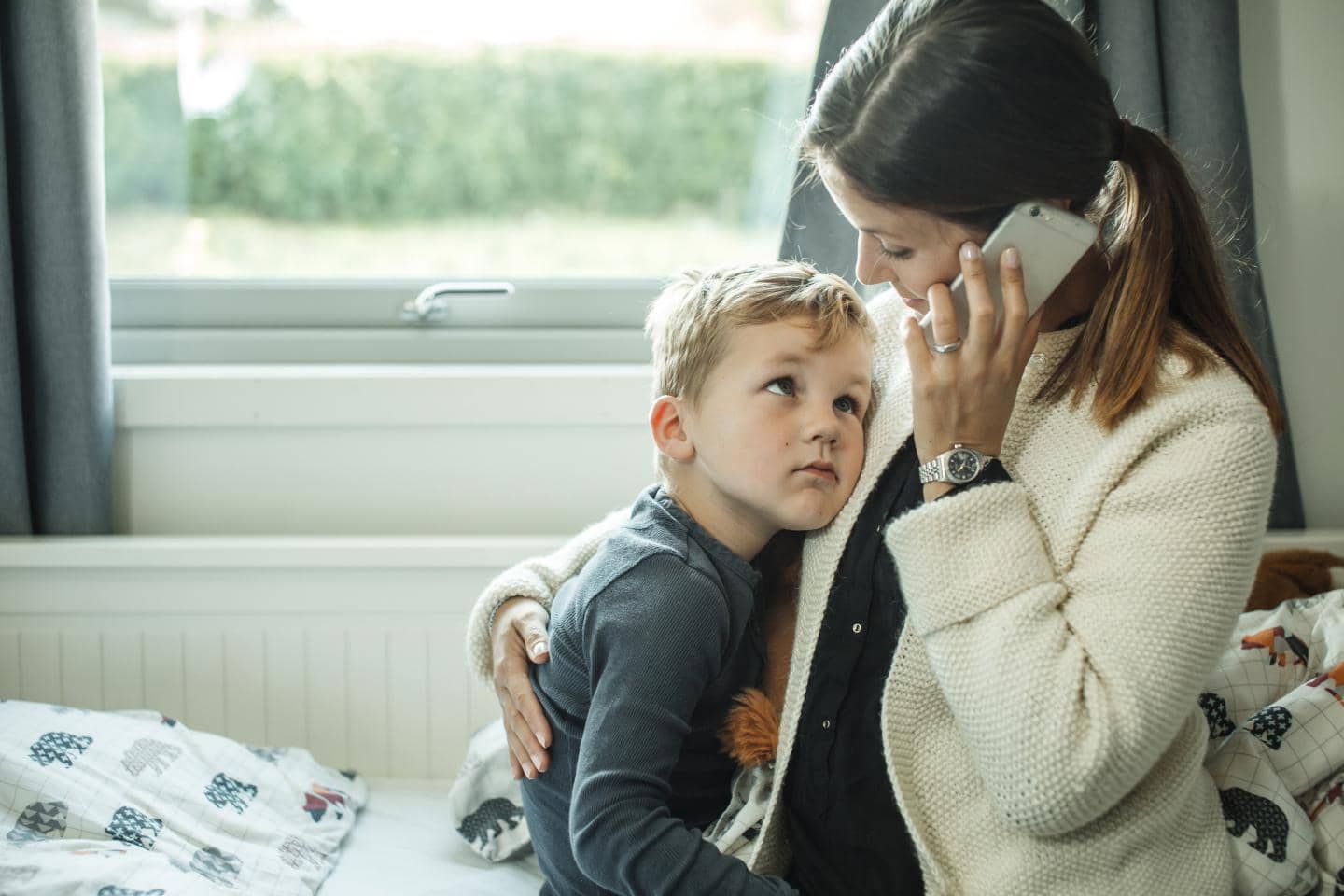 Mor holder om sit barn mens hun ringer til Tryg lægehotline