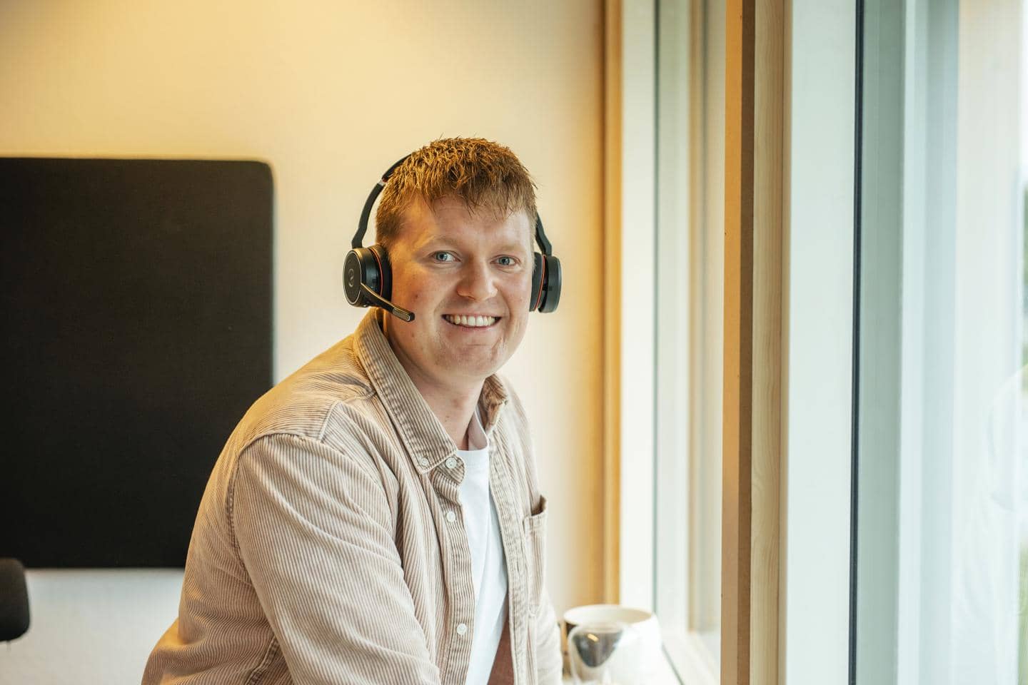 Mand, der smiler mod kameraet med headset på hovedet