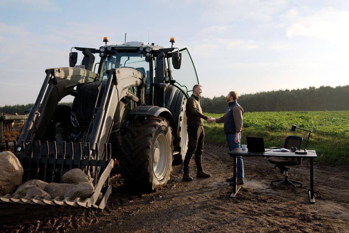 En traktor med to landmænd ved siden af